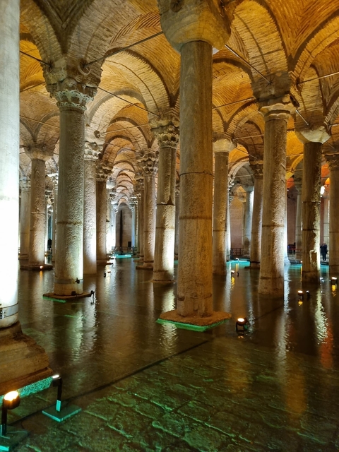       Interior of a historic water reservoir with illuminated columns.
  