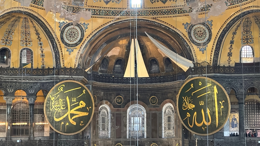       Interior of a grand mosque with large circular inscriptions.
  