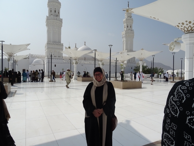 People visiting a mosque with white domes and minarets.