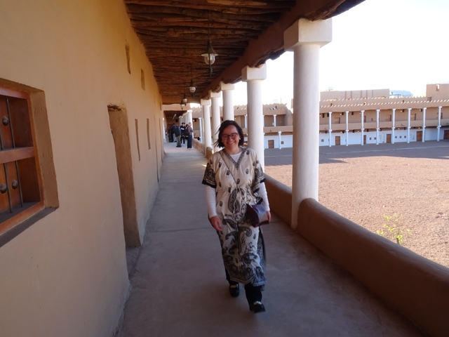 Person walking along a covered walkway with traditional architecture.