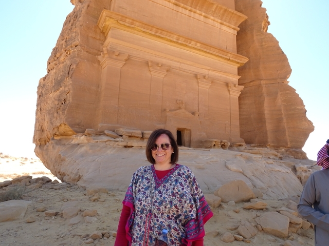 Smiling person in front of an ancient carved rock facade.