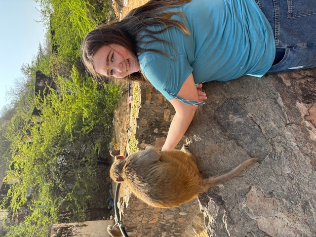       Person smiling while petting a monkey.
  