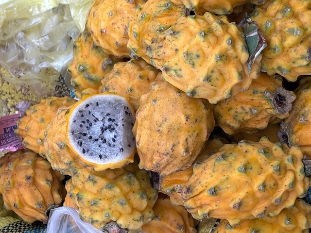       Pile of dragon fruits, one cut open showing seeds.
  