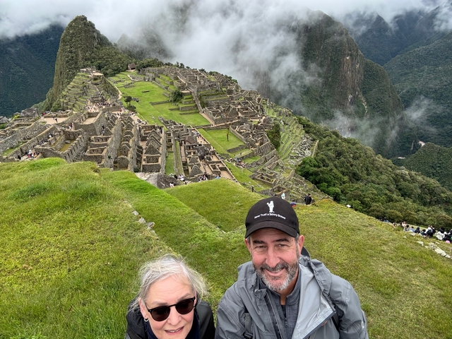       Couple smiling with Machu Picchu ruins in the background.
  