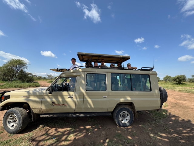       A group of tourists on a safari vehicle, exploring a savannah.
  