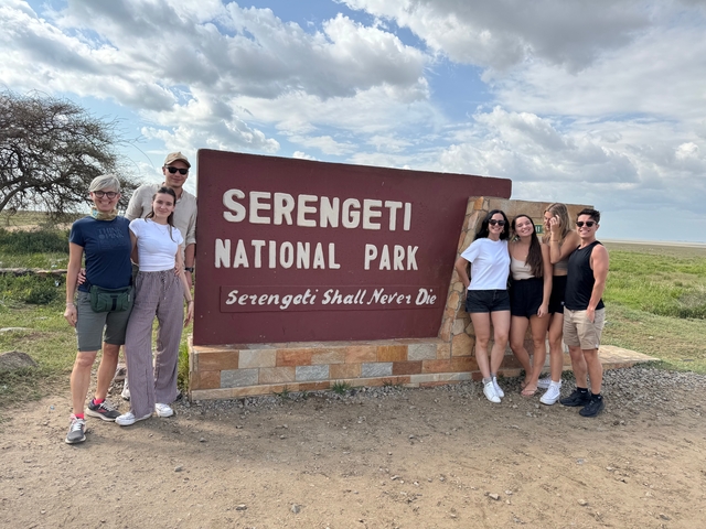       Group of people posing by Serengeti National Park sign.
  