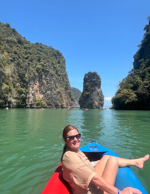       Person swimming in a tranquil bay surrounded by tall rock formations.
  