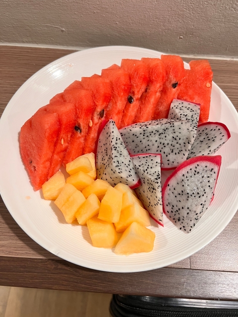      Plate of sliced tropical fruits including watermelon, pineapple, and dragon fruit.
  