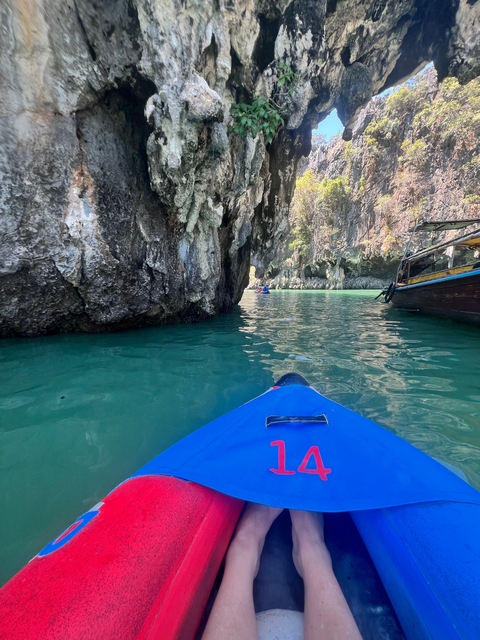       Kayaking through rocky formations in clear blue water.
  