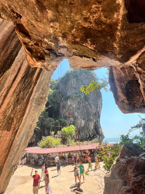 View from inside a cave looking out to a tall rock formation.