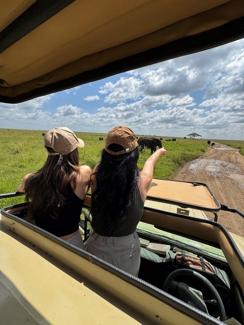 Two people observing wildlife from a safari vehicle.
