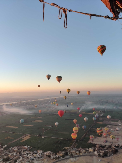 Hot air balloons floating over fields at sunrise.