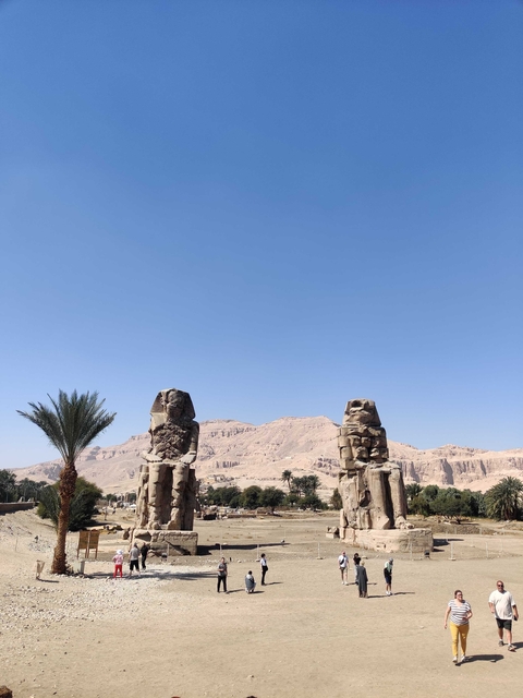       The Colossi of Memnon statues against a blue sky.
  