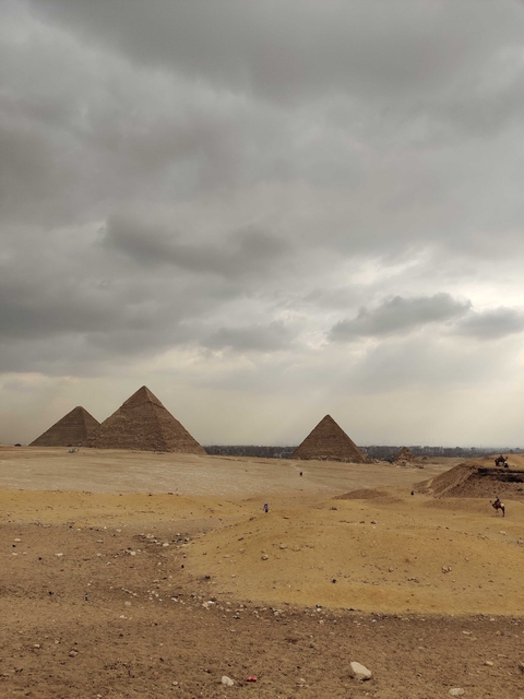 Pyramids of Giza under a cloudy sky.