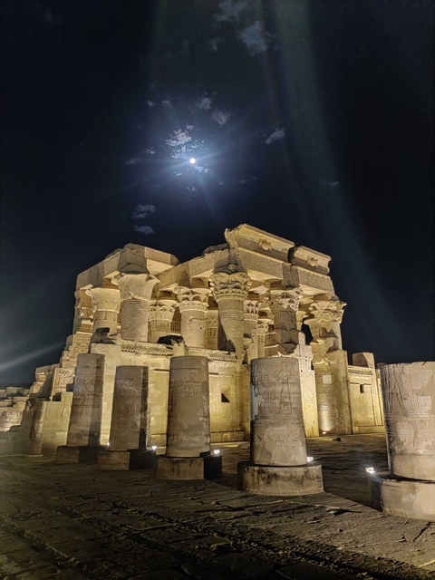 Temple illuminated at night under a moonlit sky.