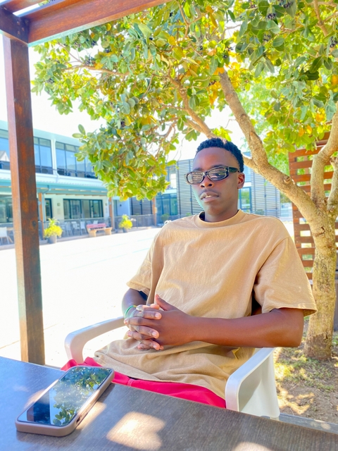 Person sitting under a tree in a sunny outdoor setting.