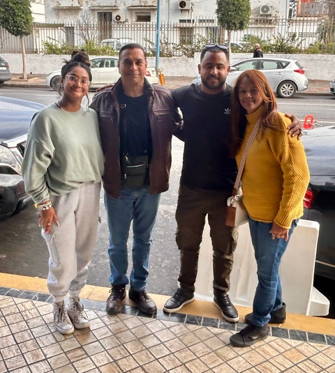       Four people posing together, casual setting.
  