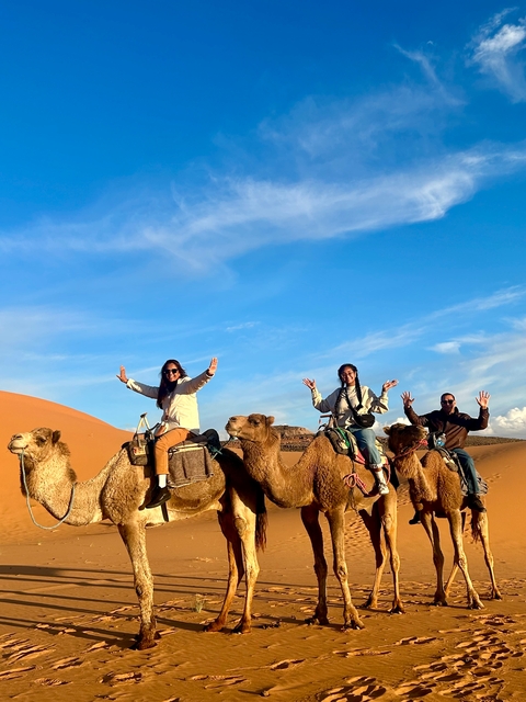       People riding camels in the desert.
  