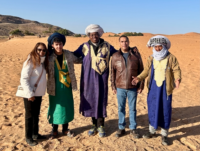       Group of people with traditional robes in desert.
  