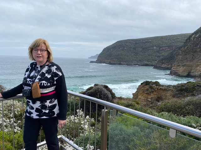 Person standing against a backdrop of coastal cliffs.