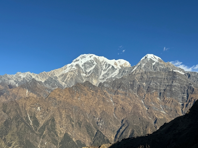 Panoramic view of sunlit mountains with blue sky.