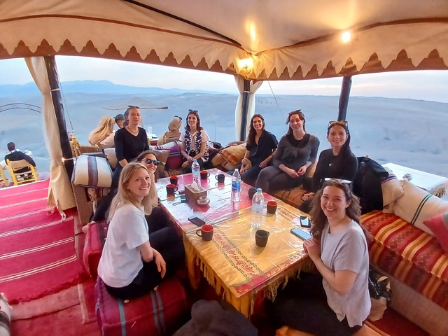 Group of women sitting in a tent with desert views.