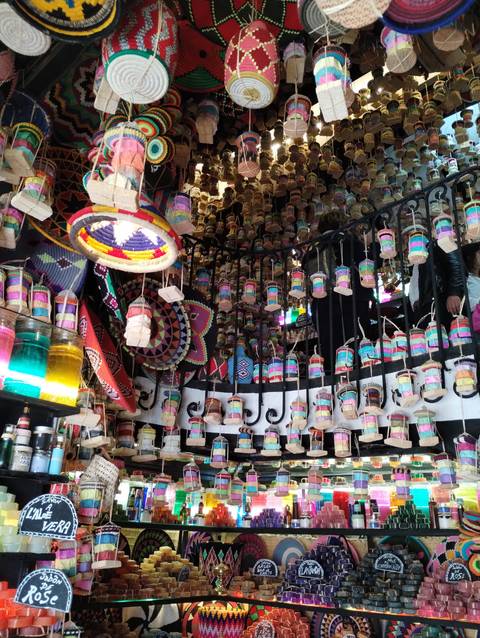 Shop interior with hanging crafts and colorful lights.