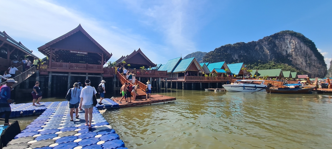       Tourists walking on floating docks in a picturesque bay.
  