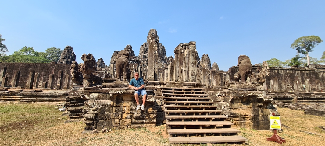       Person sitting on stairs of an ancient temple complex.
  