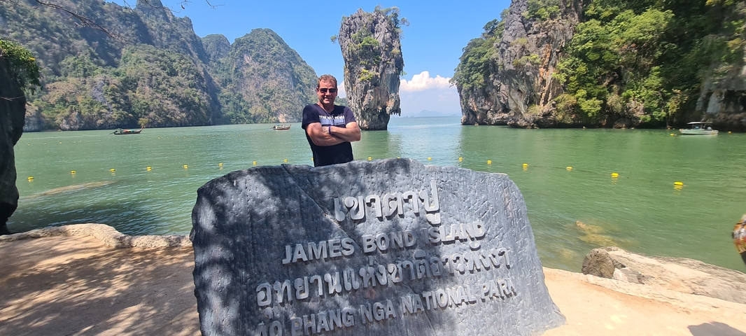       Person standing in front of the James Bond Island sign.
  
