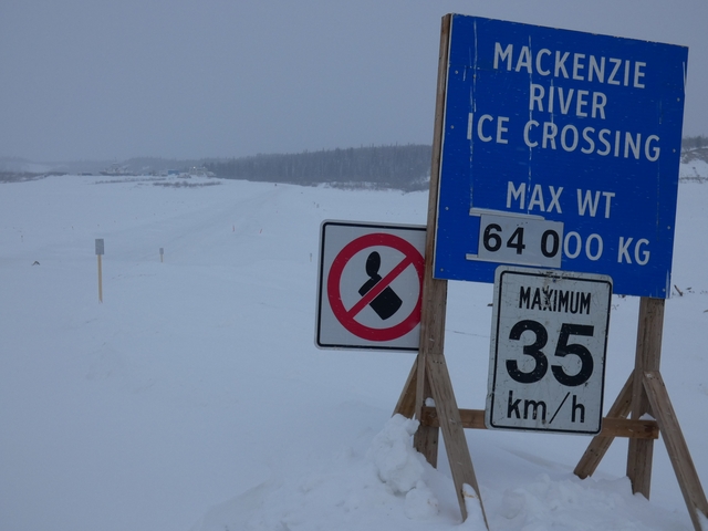 Winter landscape with snow-covered signs and distant trees.