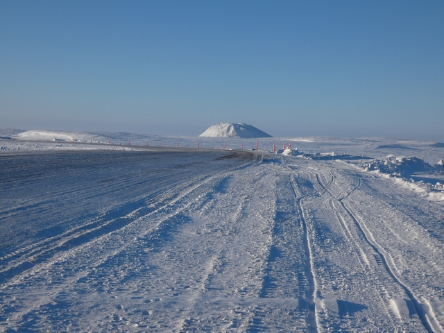       Snow-covered road with sunrise or sunset in the background.
  