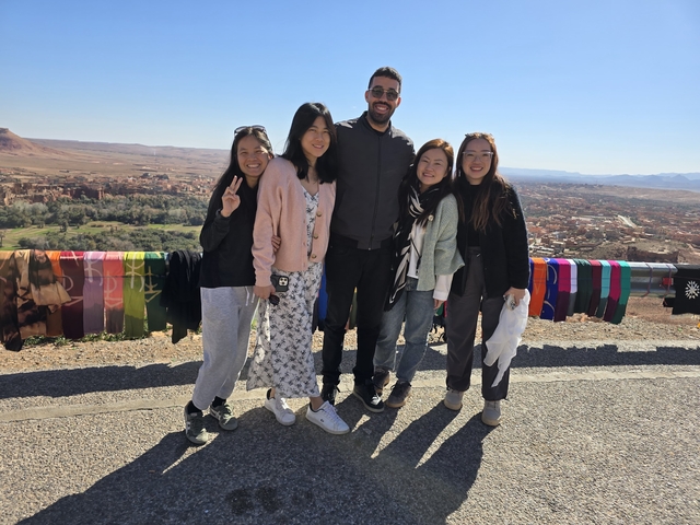       Group of people posing with colorful fabric in the background
  
