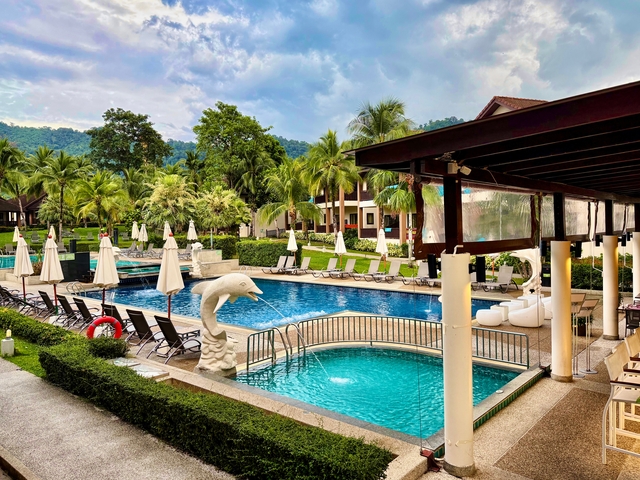       Luxury resort pool area with sun loungers and a dolphin statue.
  