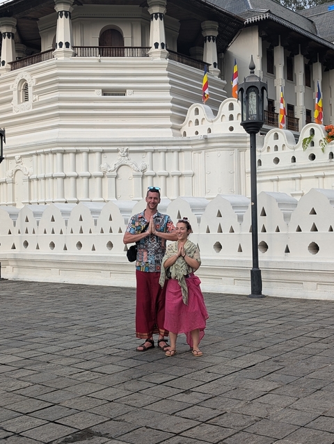 A couple in traditional attire in front of a white temple.