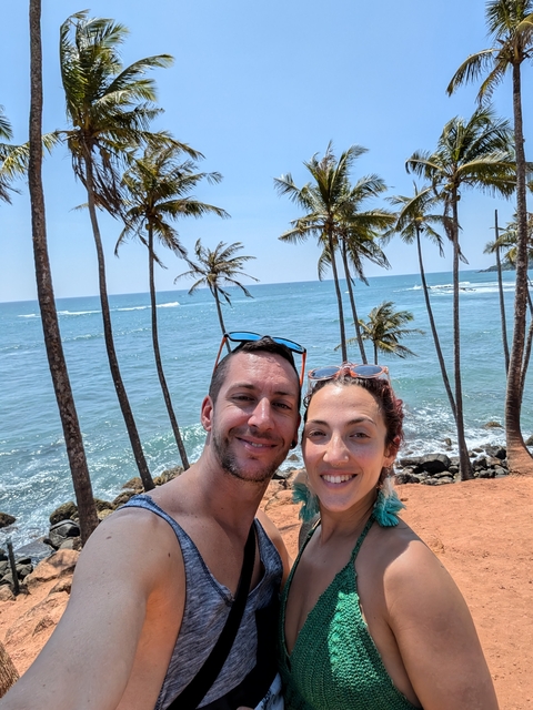 Couple taking a selfie on the beach with palm trees.