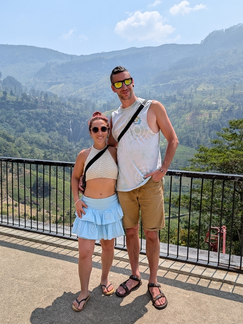       Couple posing with a scenic valley and waterfall in the background.
  