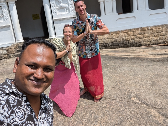 Three people posing with a smile, wearing traditional attire.