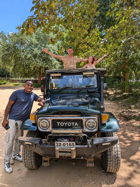 Two people standing on a jeep, posing for a photo.
