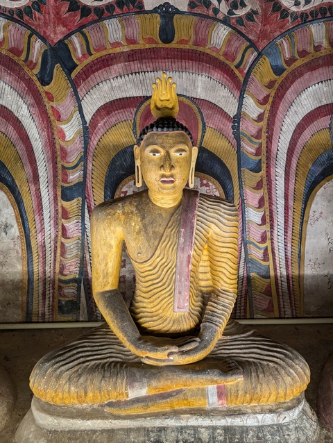 Statue of Buddha in a richly decorated alcove.