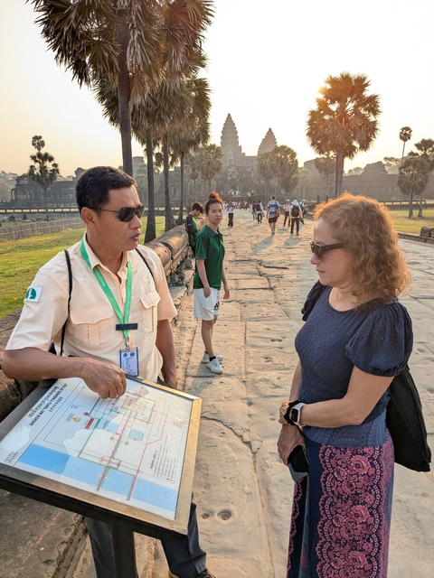       Two people in conversation with an ancient temple in the background.
  