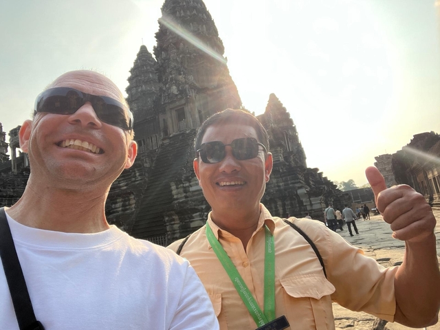       Two people smiling in front of an ancient temple.
  