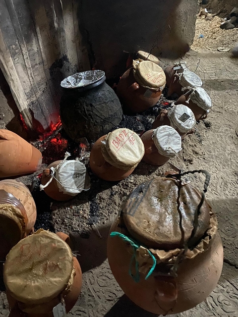 Clay pots in a traditional cooking setting with a stove.