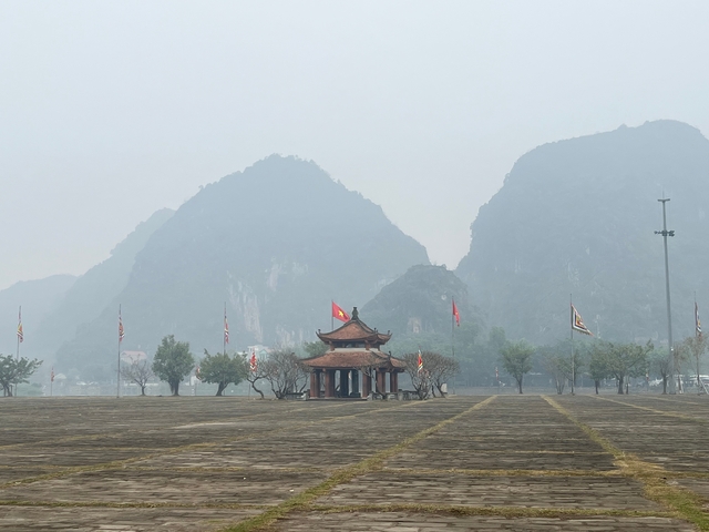 A pavilion with flags in a misty mountainous setting.