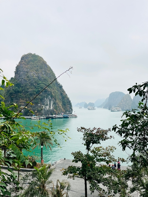      Boats on a bay surrounded by karst islands under cloudy sky.
  