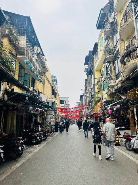 A bustling street market with red banners overhead.