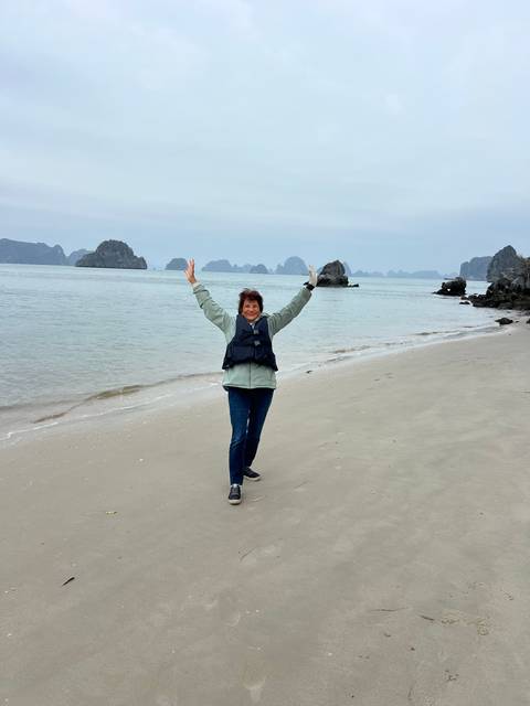       A person standing on a beach with sea stacks in the background.
  