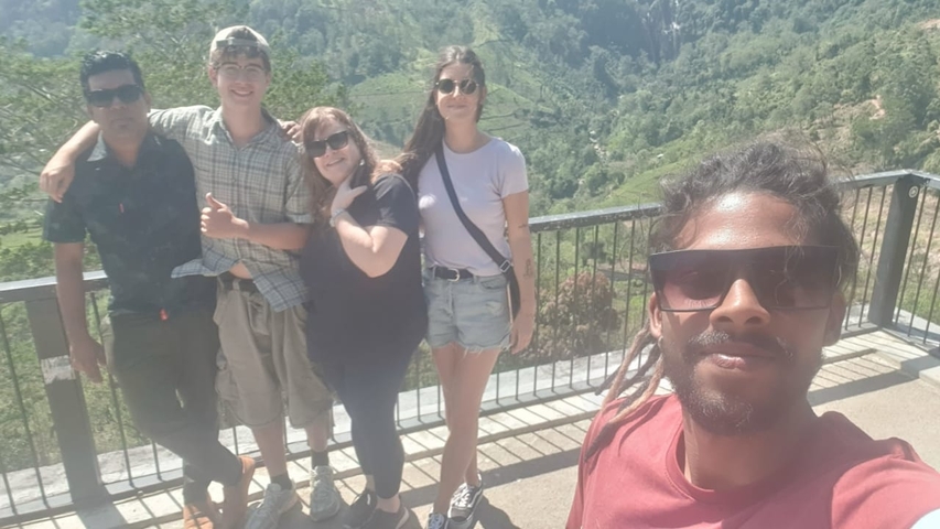 Group of people taking a selfie with a scenic background.