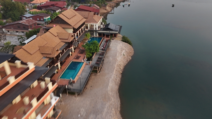 Aerial view of riverside resort buildings with swimming pools.