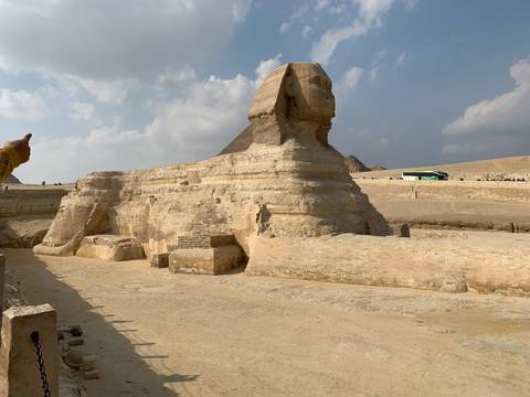       The Sphinx with tourists and a bus nearby.
  
